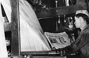 Cleveland Press employee watches newspapers roll off presses, 1938
